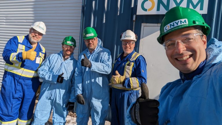 five men with protective clothing in front of the technological showcase of the Onym Group