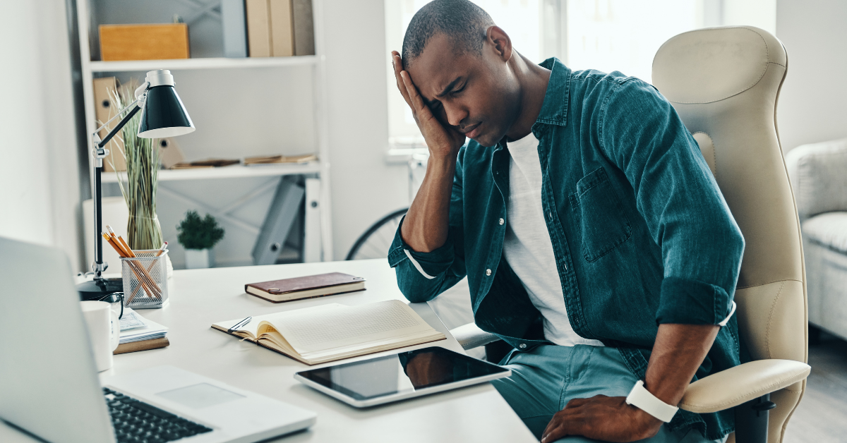 Consultant TI, comment choisir son institution financière homme noir dans la trentaine, consultant TI, se tient la tête, désespéré, devant son ordinateur.